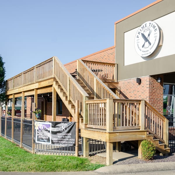 Prime Time Pub & Grill exterior with a large wooden deck, stairs, and a banner listing awards.