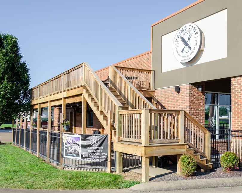 Prime Time Pub & Grill exterior with a large wooden deck, stairs, and a banner listing awards.