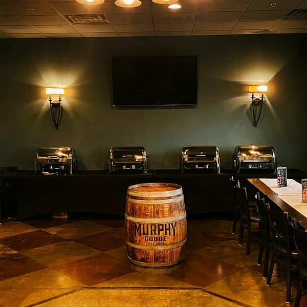 A private dining room with a buffet setup, long tables, and a "Murphy-Goode" wine barrel.