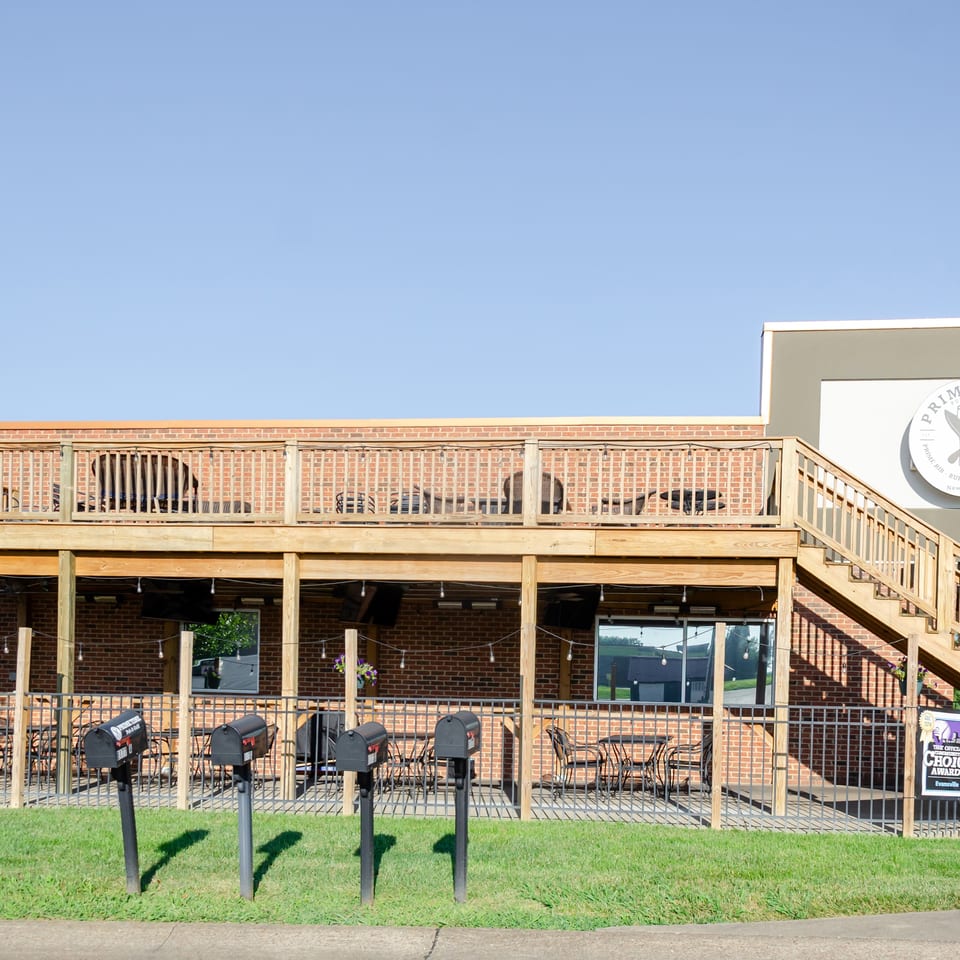 Exterior of Prime Time Pub & Grill, showing a two-story brick building with outdoor patio seating.